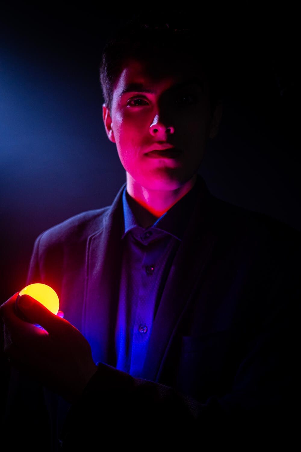 Rado Sheytanoff lit in red and blue, holding a glowing orb